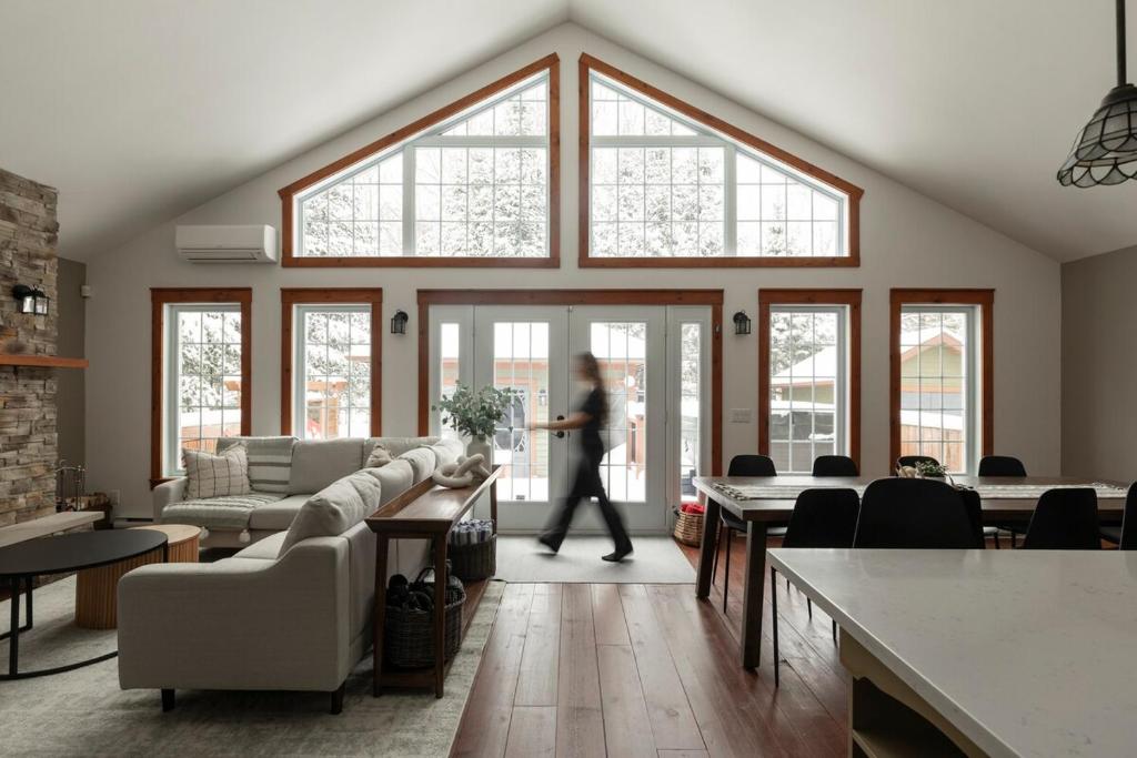 une personne traversant un salon avec de grandes fenêtres dans l'établissement Pool - Kid Game Room - HotTub, à Saint-Faustin–Lac-Carré