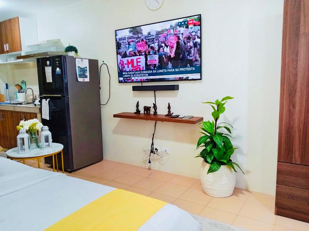 a kitchen with a refrigerator and a tv on the wall at Norman Condominium Unit Rental Sea View in Dumaguete