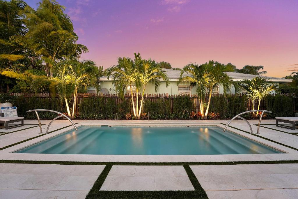 a swimming pool in a yard with palm trees at Lovely 1 Bedroom - Walk to Waterfront in West Palm Beach