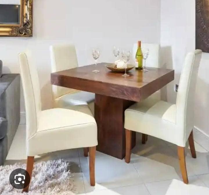 einen Esstisch mit weißen Stühlen und einem Holztisch in der Unterkunft Gods Heritage Apartments and properties nig ltd 