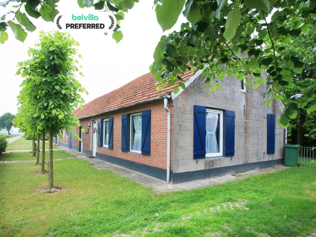 OspelにあるFarmhouse in Nederweert near Canal Trailsの青窓と木が特徴のレンガ造りの家