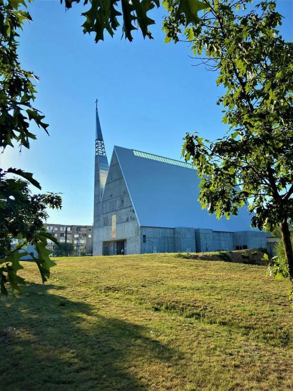 a church with a steeple on top of a field at butas in Vilnius