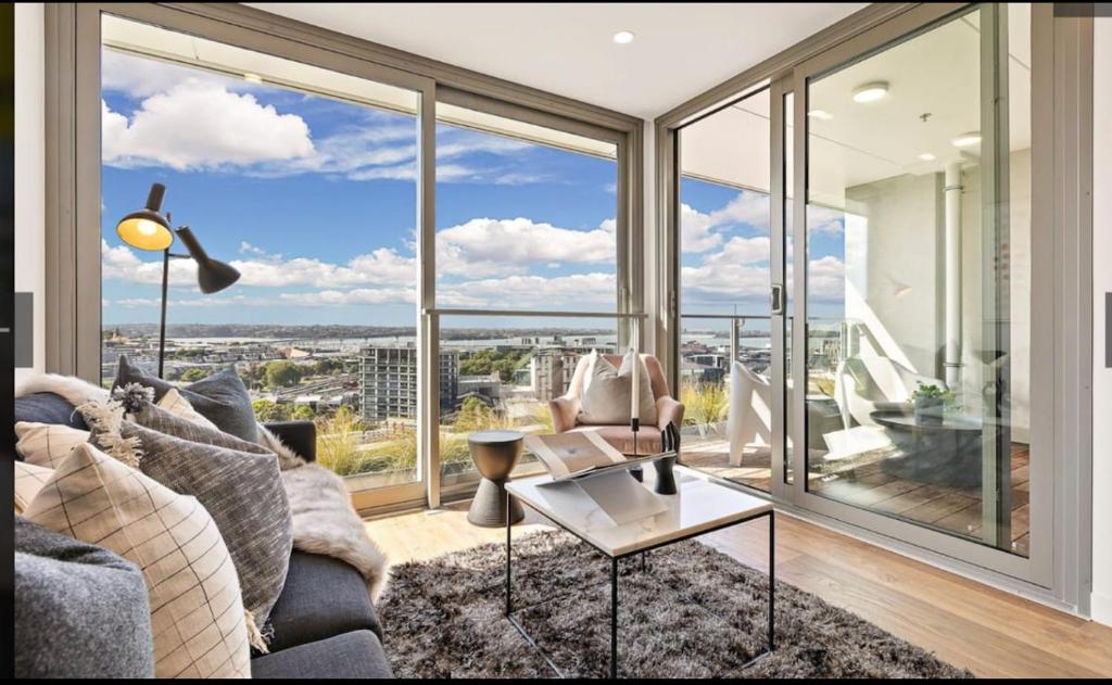 Una sala de estar con un sofá y una ventana grande. en CBD luxury Apartments Union green with sea view, en Auckland