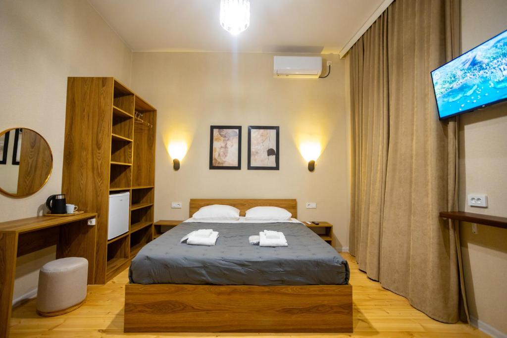 a bedroom with a bed and a flat screen tv at Edmar Boutique Stay in Kutaisi
