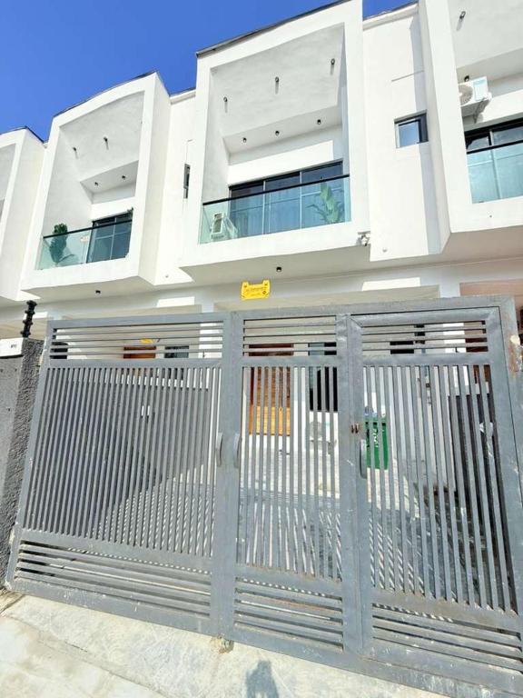a white house with a gate in front of it at UV Residence in Ikota