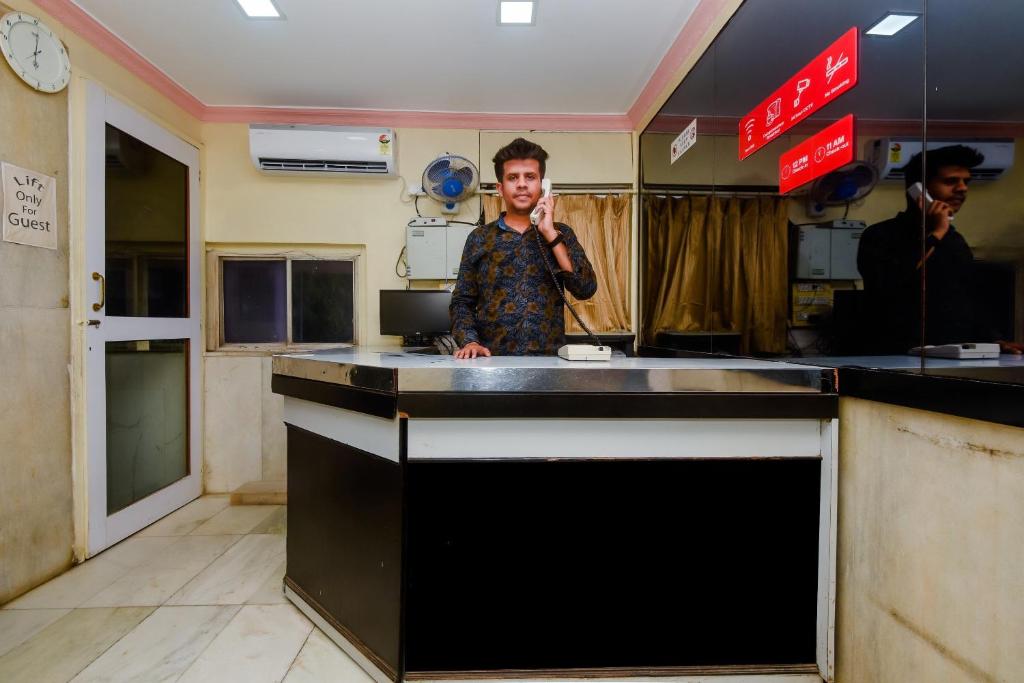 Een man die in een keuken staat te praten met een mobiele telefoon. bij Hotel O Prince Palace in Mumbai