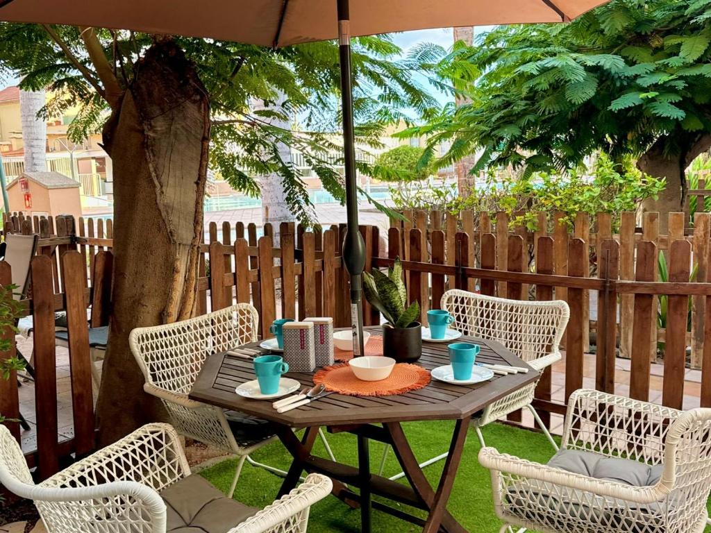 a table with chairs and an umbrella on a patio at Oasis Lemon in Maspalomas