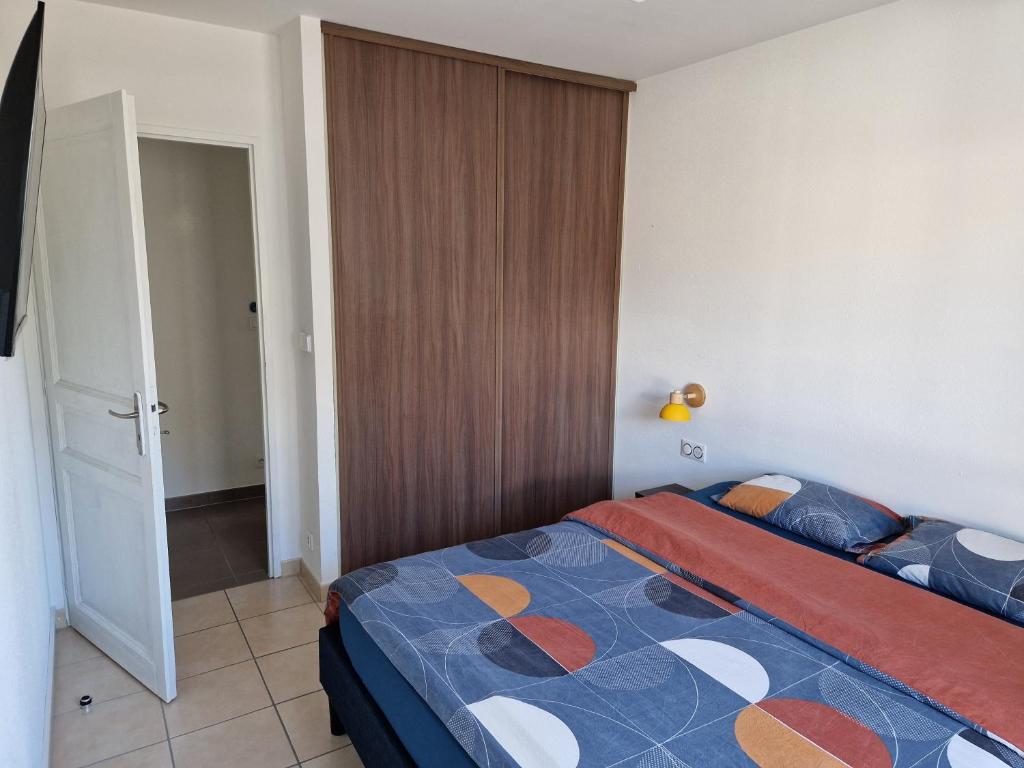 a bedroom with a bed with a blue and orange comforter at Chambre accueillante in Prévessin