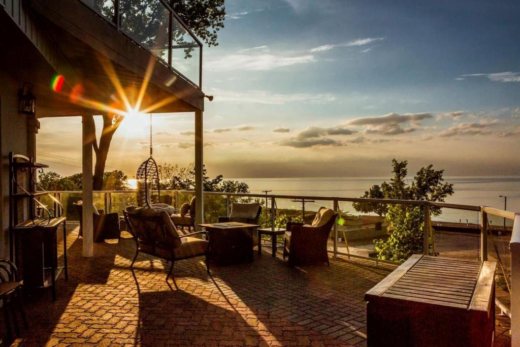 un patio avec une table et des chaises et le coucher du soleil dans l'établissement Lakeside Villa with a Hot Tub and Amazing Views on Lake Michigan, Indiana, à Miller