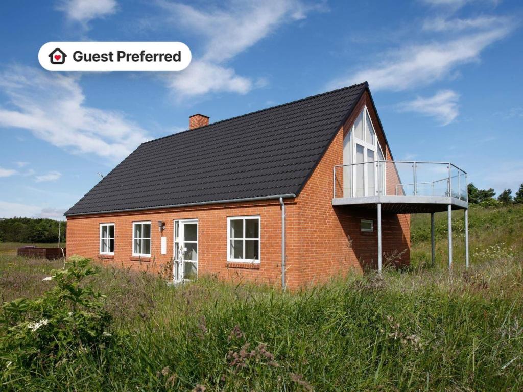 a red house with a black roof in a field at Secluded Retreat near Sea - By Traum Ferienwohnungen in Vigsø
