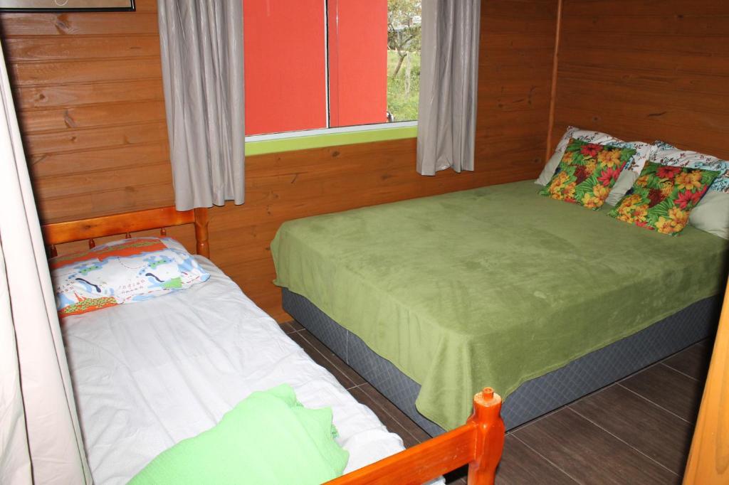 a small room with two beds and a window at Cabanas do Lorde in Praia do Rosa