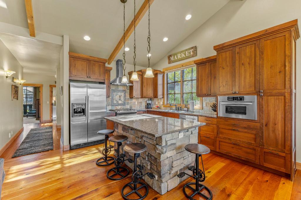 a kitchen with wooden cabinets and a stone island with bar stools at Ravenswood- Lake views- downtown greystone with air conditioning in McCall