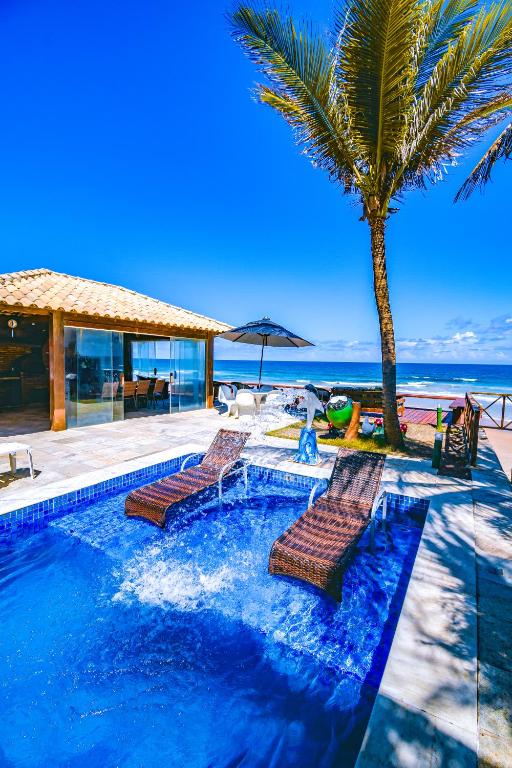 una piscina con tumbonas y una palmera en Mar a Vista Charme by Concavus, en Porto de Galinhas