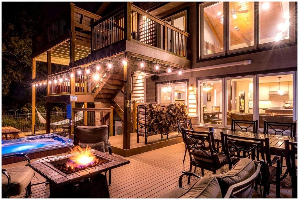 a house with a deck with a fireplace and a pool at Luxurious Villa with Hot-tub, Fire Pit and Games in Gary, Indiana in Miller