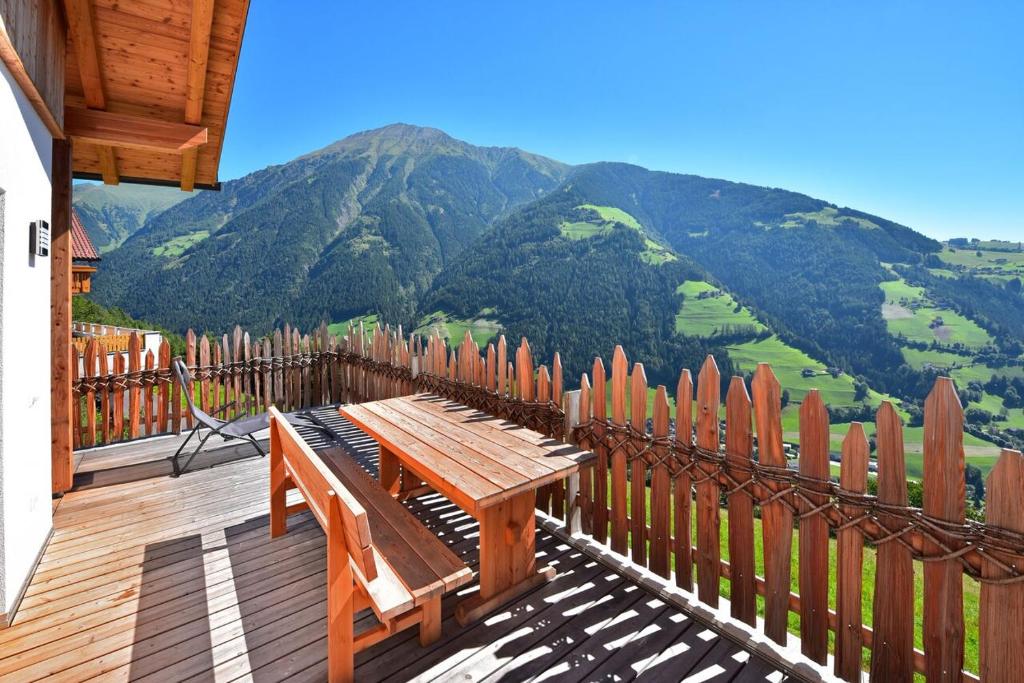 a wooden deck with a bench and a fence with mountains at Tratterhof Apartments in Vallarga