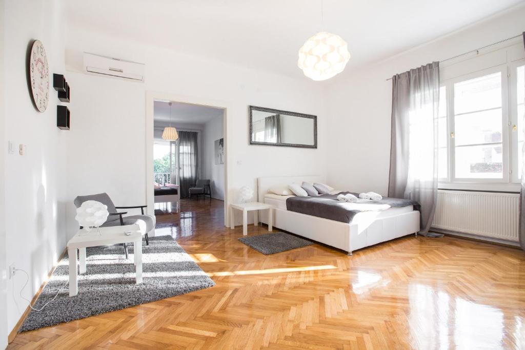 a white bedroom with a bed and a wooden floor at Apartment Ribnjak in Zagreb