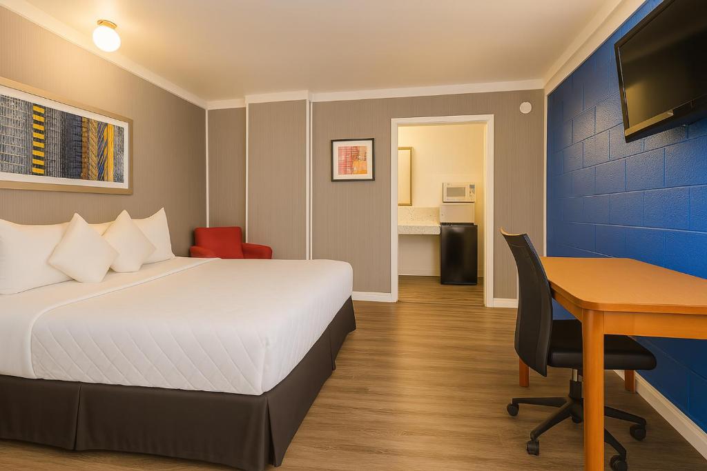 a hotel room with a bed and a desk and a table at Sawmill Lodges Motel in Hennessey