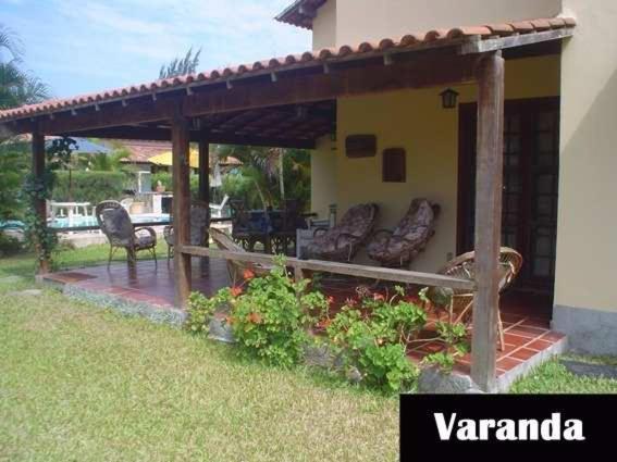 a wooden pergola on a house with chairs on a patio at Casa em Cabo Frio com Piscina e Acesso a Praia in Tamoios