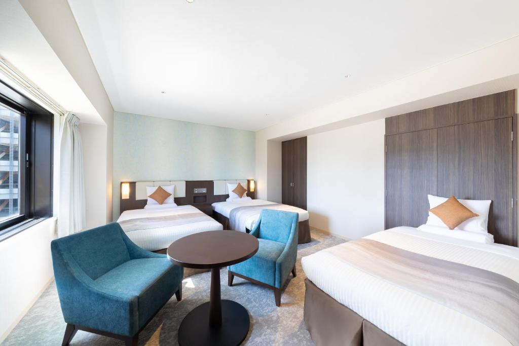 a hotel room with two beds and a table and chairs at Art Hotel Niigata Station in Niigata