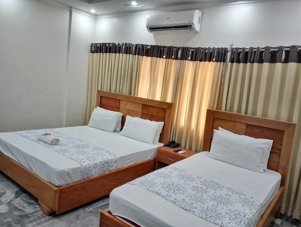a bedroom with two beds and a window at Clifton BnB in Karachi