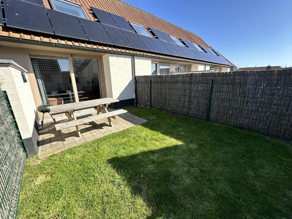 Un banco de madera con paneles solares en el costado de una casa. en Westhinder I H30, en Koksijde