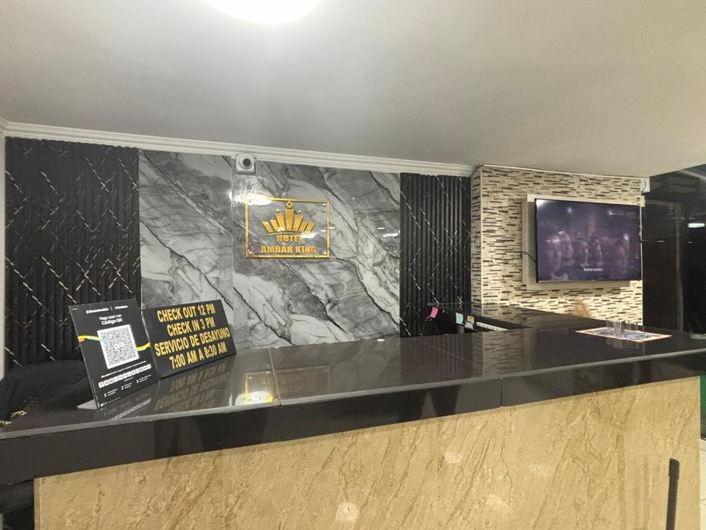 a lobby with a black counter and a television at Hotel AMBAR KING in Bogotá