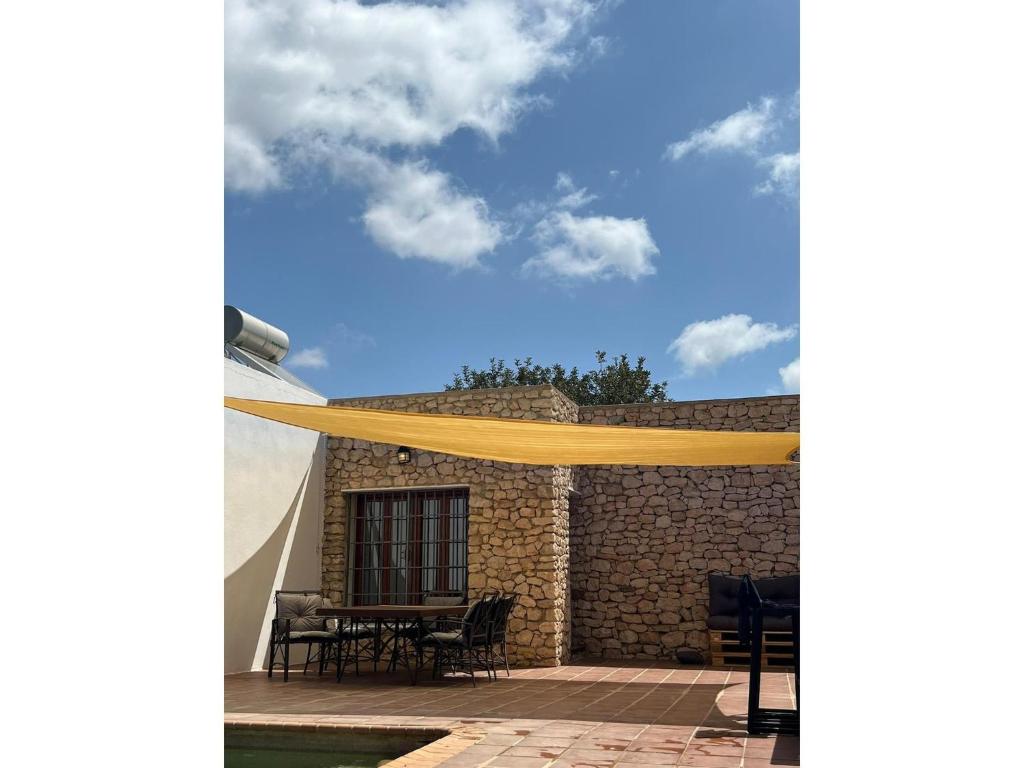 a patio with a yellow canopy on top of a building at Stone house with private pool in Agua Amarga in Los Cerrillos