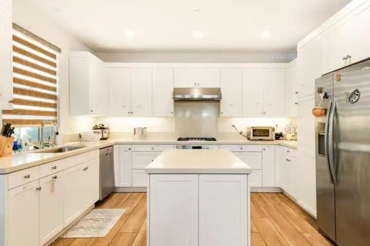 a kitchen with white cabinets and a stainless steel refrigerator at Private suite downstairs in Irvine