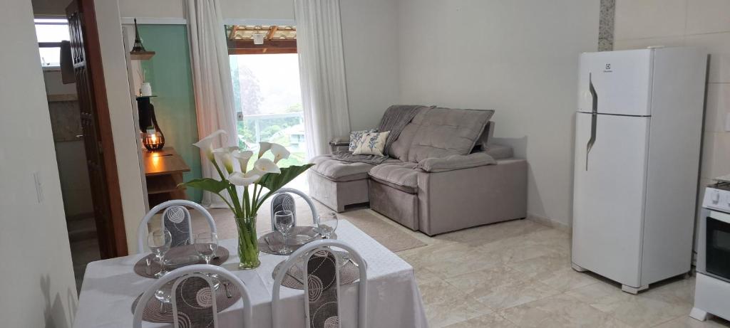 a living room with a refrigerator and a table with white flowers at Casa Bello Monte in Venda Nova do Imigrante