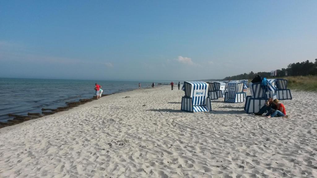 a beach with chairs and people sitting on the sand at Loui´s FeWo Wiek in Wiek auf Rügen 