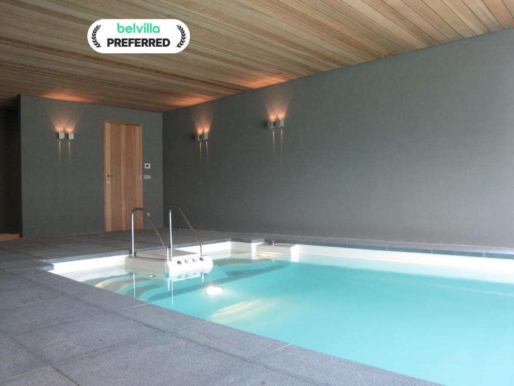 a large swimming pool in a room with a sign at Beernem Farmhouse with Pool in Beernem