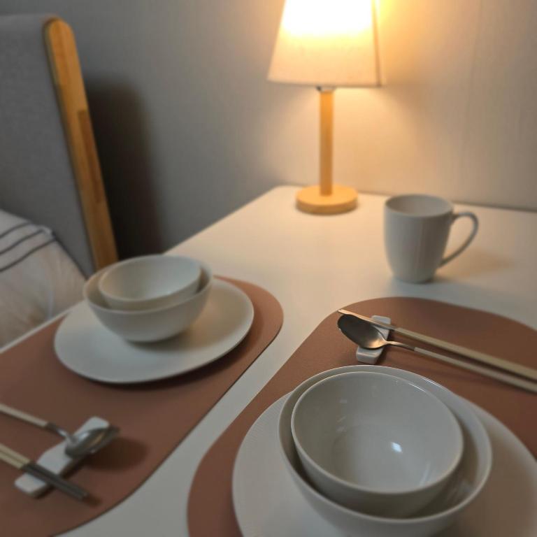 a table with two plates and two cups on it at One Stay in Gwangmyeong