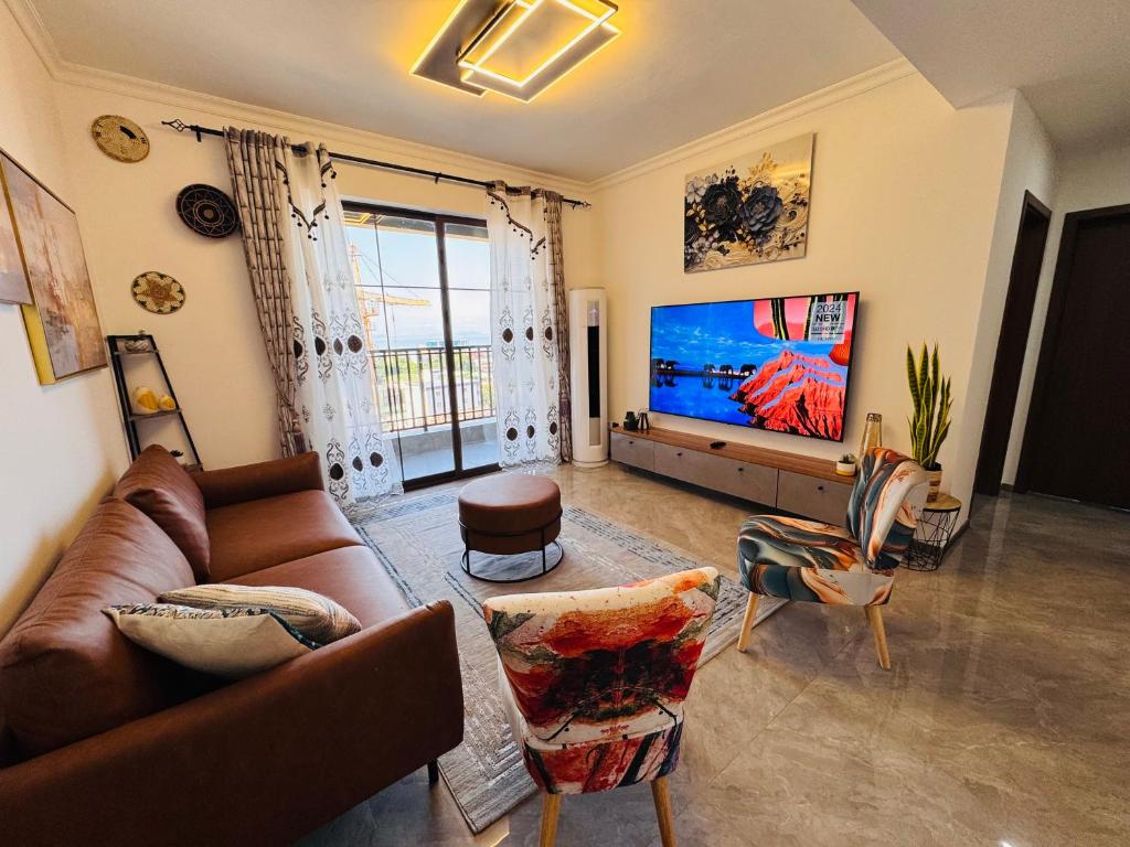 un salon avec un canapé et une télévision à écran plat dans l'établissement Kipé Plaza platinium Vue Mer Appartement 2 Chambres, à Conakry