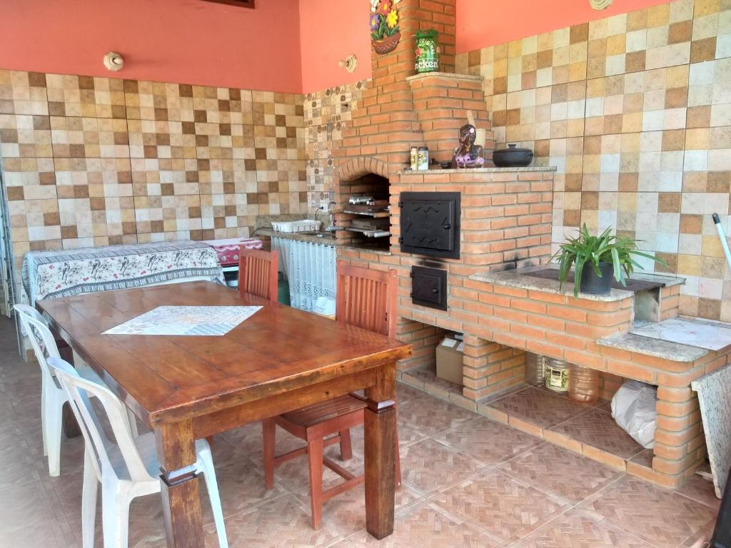 a kitchen with a wooden table and a brick oven at Casa Temporada Bertioga- Indáia in Bertioga