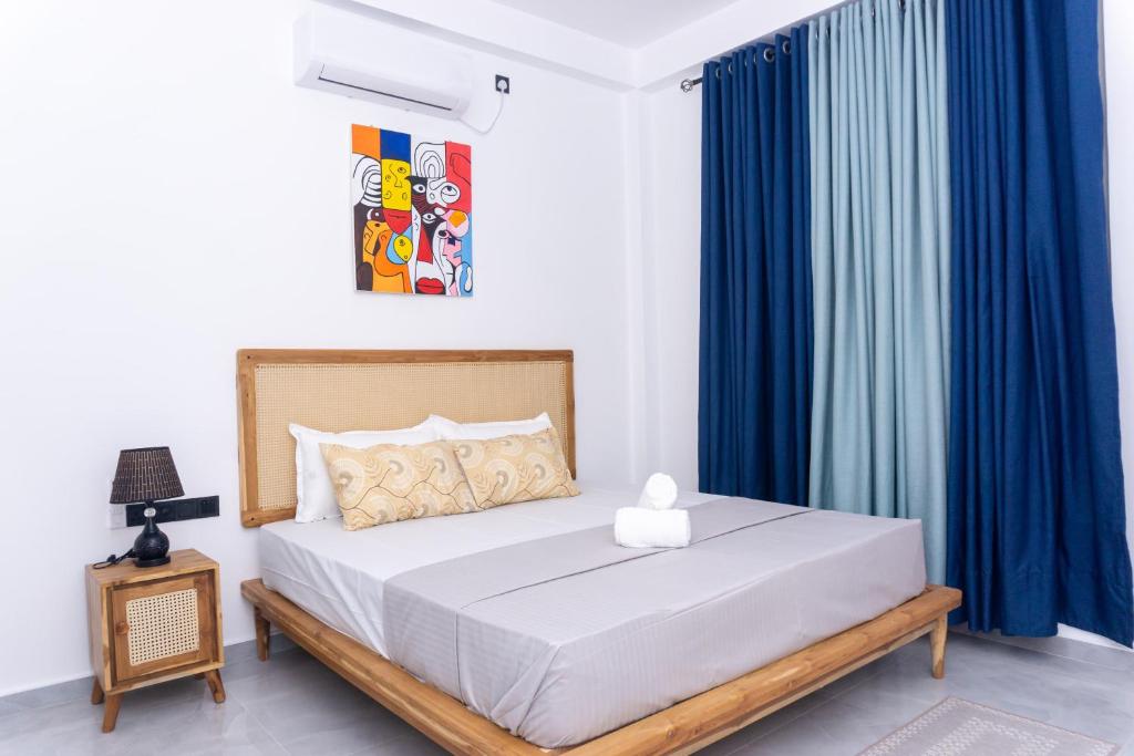 a bedroom with a large bed with blue curtains at Rylennest in Denipitiya