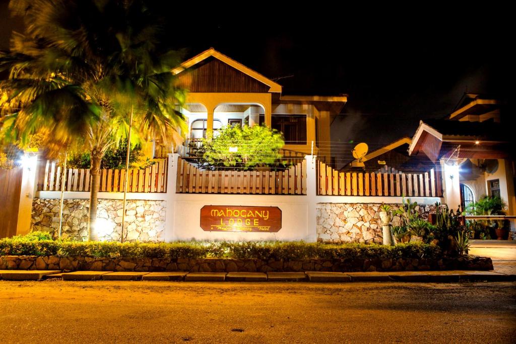 une maison avec un panneau devant elle la nuit dans l'établissement Mahogany Lodge, Cantonments, à Accra
