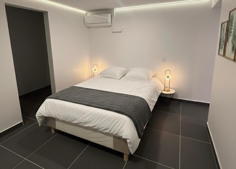 a bed in a white room with two lamps at Casa Nalya in Kourou