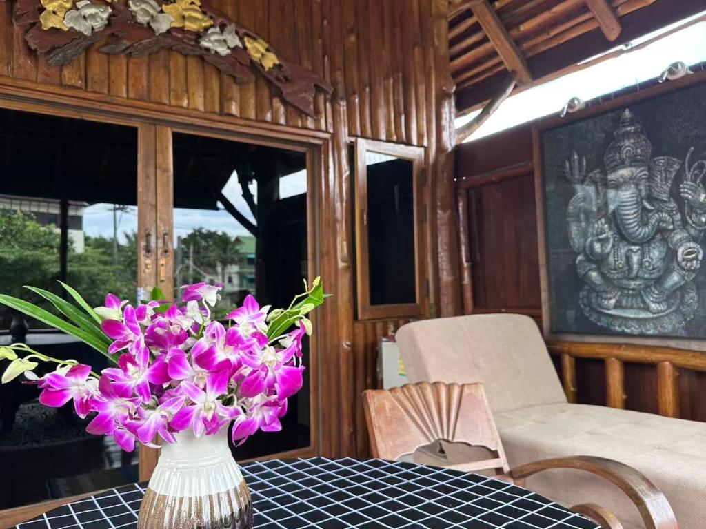 un vase rempli de fleurs violettes sur une table dans l'établissement Thai Tom s GuestHouse, à Chiang Mai