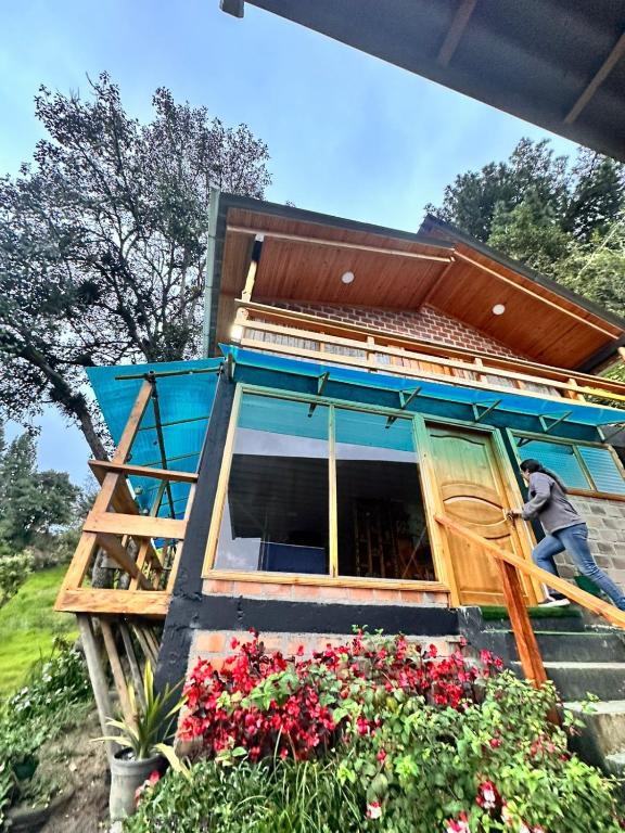 a man working on a house with flowers at Cabaña arcoiris del lago # 6 in Pasto