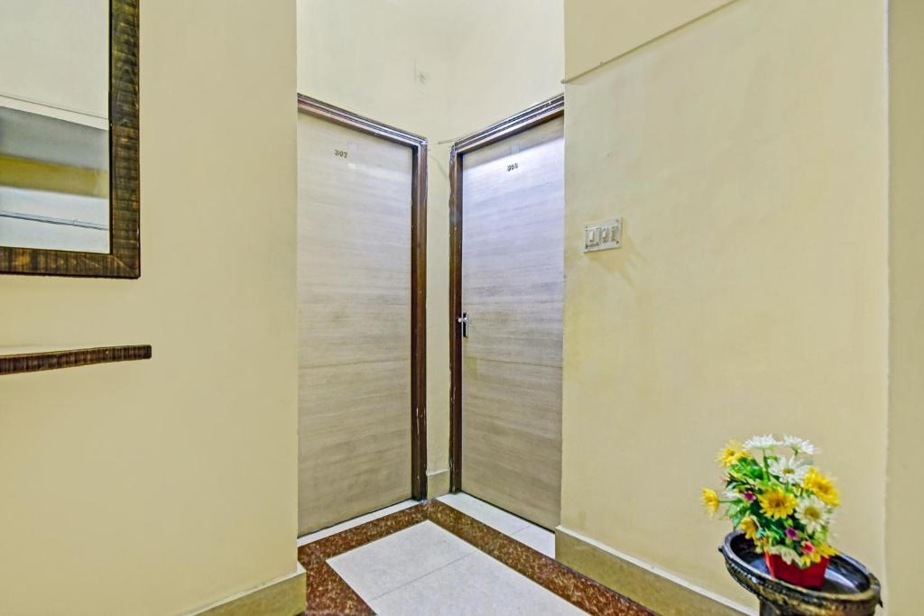 a walk in shower in a room with a vase of flowers at Hotel O jaapon in Calcutta Bara Bazar