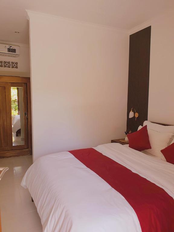 a bedroom with a large bed with red and white sheets at GYANA House in Ubud