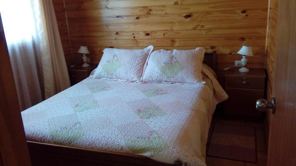 a bedroom with a bed with a wooden wall at Cabañas Sol de Buchupureo in El Cerrillo