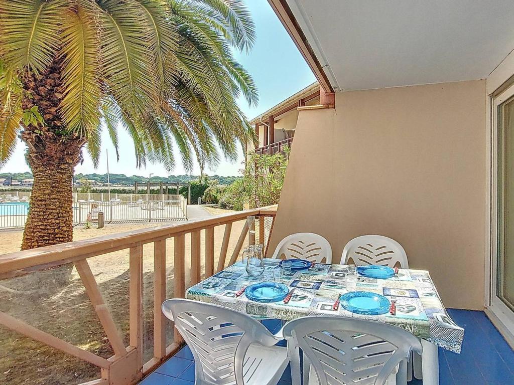 einen Tisch und Stühle auf einem Balkon mit einer Palme in der Unterkunft Appartement T3 pour 6 pers. avec terrasse et accès piscine - FR-1-857-1 in Vieux-Boucau-les-Bains
