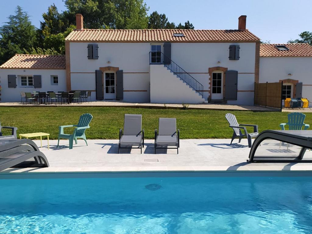 ein Haus mit Stühlen und einem Pool davor in der Unterkunft Spacieux Gîtes en Vendée avec Piscine Chauffée - FR-1-426-596 in Soullans