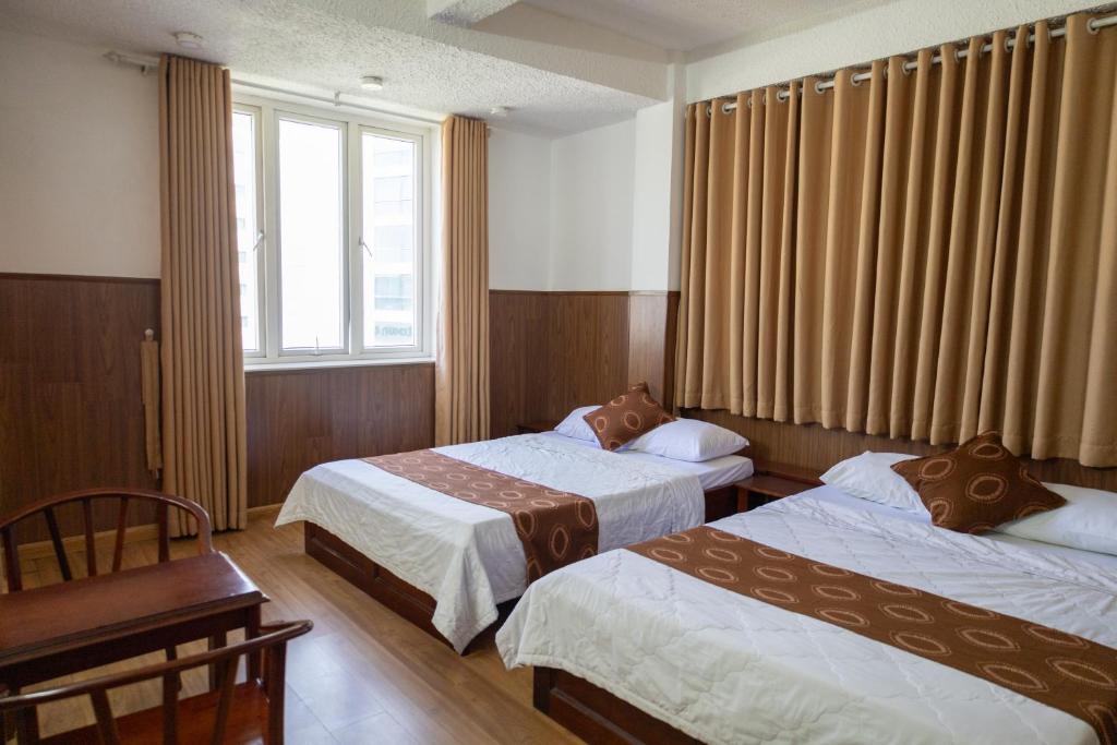 a hotel room with two beds and a window at Minh Châu Hotel in Kon Rung (1)