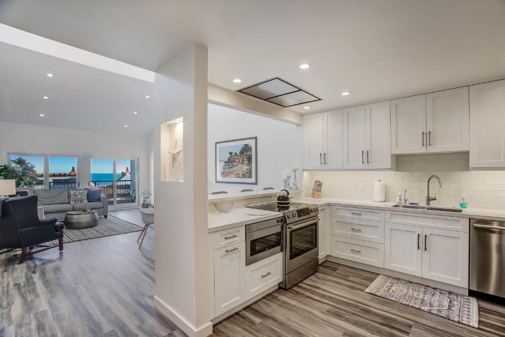 a kitchen with white cabinets and a living room at Leadbetter Beach Retreat in Santa Barbara
