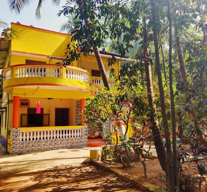 a yellow house with a balcony in front of it at Deepdaya Cottage in Alibag