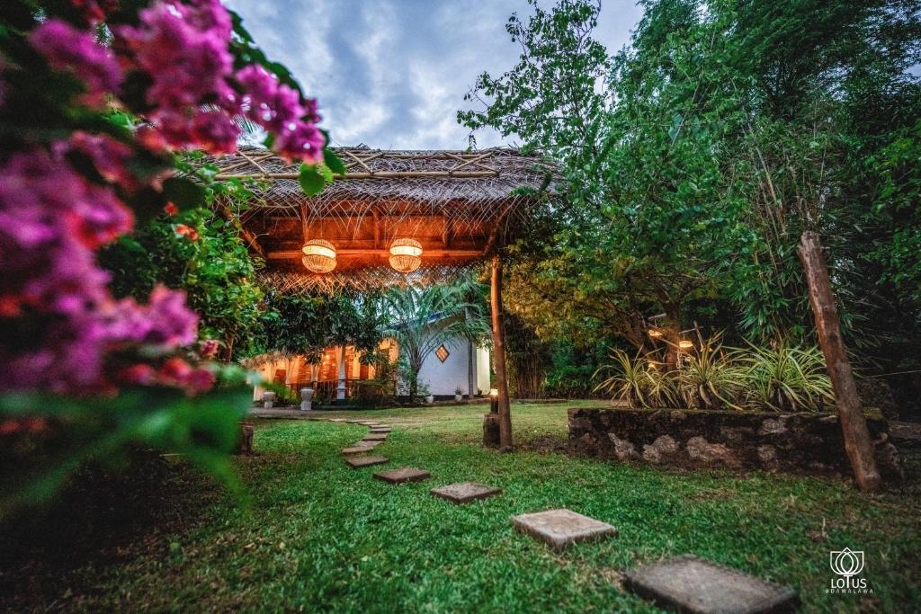 a garden with a pavilion with flowers and rocks at Lotus Udawalawe in Udawalawe