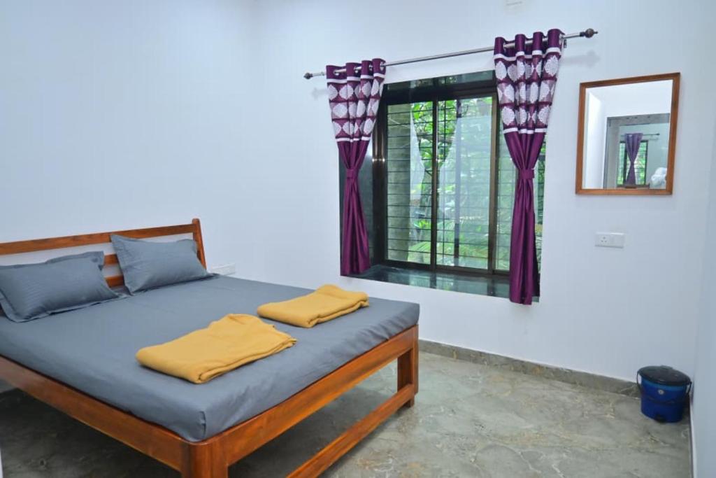 ein Schlafzimmer mit einem Bett und einem Fenster mit Vorhängen in der Unterkunft Kokan beach cottage in Alibag