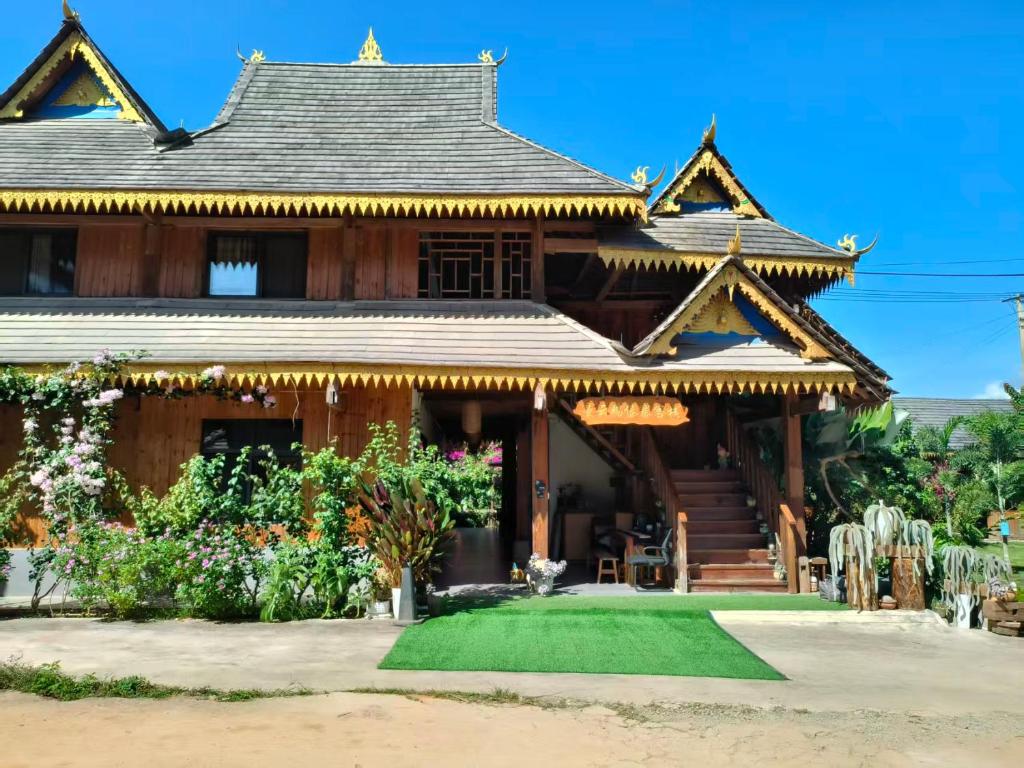 a house with a green lawn in front of it at Jinghong Manyun Dai Village Inn in Jinghong